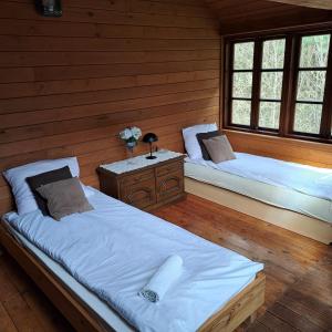 2 camas en una habitación con paredes y ventanas de madera en Domek wycieczkowy 