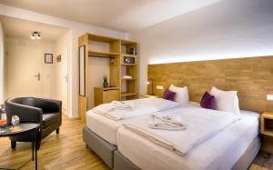 una habitación de hotel con una cama grande y una silla en Brauereigasthof Bären en Titisee-Neustadt