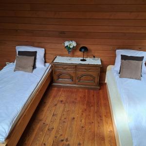 un dormitorio con 2 camas y una mesa con un jarrón de flores en Domek wycieczkowy 