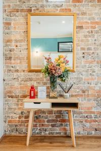 una mesa con un espejo y un jarrón de flores. en Newtown Cozy Stays, en Sídney