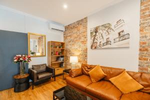 sala de estar con sofá de cuero marrón y silla en Newtown Cozy Stays en Sídney