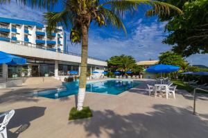 uma piscina com uma palmeira em frente a um hotel em Ingleses Praia Hotel em Florianópolis