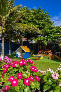 un parque con parque infantil y flores rosas en Ingleses Praia Hotel, en Florianópolis