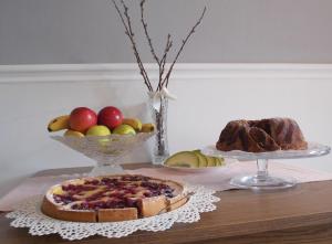 uma mesa com dois pratos de fruta e um bolo em Éden Villa Apartmanház em Balatonfüred