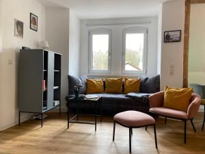a living room with a black couch and two chairs at Stilvolles Appartement im Herzen Bambergs in Bamberg
