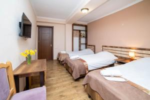 a room with three beds and a table with yellow flowers at Guest House Kavkasioni 33 in Telavi