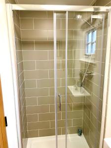 a shower with a glass door in a bathroom at Clay Bank Huts, Roseberry Shepherds Hut in Ingleby