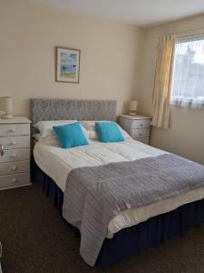 a bedroom with a large bed with blue pillows at Cosy Cornish Chalet Camelford Port Isaac in Camelford