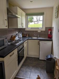 uma cozinha com armários brancos e uma janela em Cosy Cornish Chalet Camelford Port Isaac em Camelford