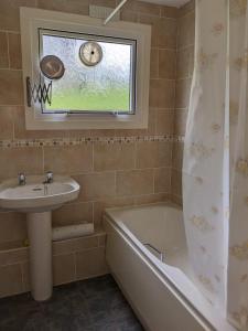 a bathroom with a sink and a bath tub and a window at Cosy Cornish Chalet Camelford Port Isaac in Camelford