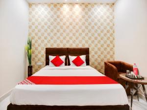 Schlafzimmer mit einem Bett mit roten Kissen und einem Tisch in der Unterkunft OYO Flagship Golden A in Ludhiana