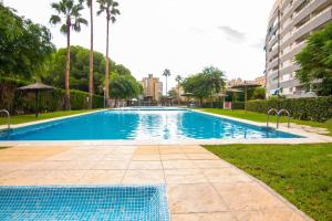 een groot blauw zwembad met bomen en gebouwen bij Vistas del Mar Oasis in El Campello