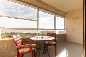 een tafel en stoelen in een kamer met ramen bij Vistas del Mar Oasis in El Campello