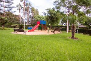 een speeltuin in een park met twee banken en een glijbaan bij Vistas del Mar Oasis in El Campello