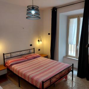 a bedroom with a bed with a striped comforter and a window at Giallo Sole in Colleferro