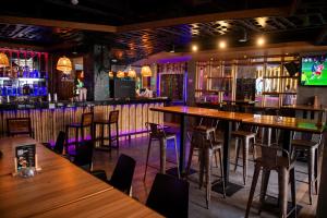 a bar with wooden tables and chairs and a tv at Mad Monkey Phuket in Patong Beach