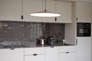 a kitchen with white cabinets and a sink at By Friso Den Haag in Scheveningen