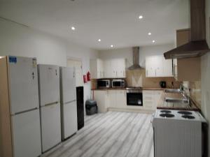 a large kitchen with white appliances and wooden floors at Thales Home FFDblBath6 in Barking