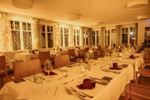 een restaurant met witte tafels en stoelen en kerstverlichting bij Der Charlottenhof in Ahrenshoop