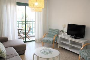 ein Wohnzimmer mit einem Sofa und einem TV in der Unterkunft Playa San Juan 3 bd apartment by the sea in Playa de San Juan