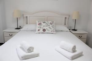 ein weißes Bett mit zwei Kissen und Handtüchern darauf in der Unterkunft Playa San Juan 3 bd apartment by the sea in Playa de San Juan