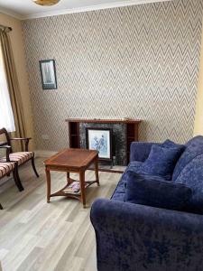 a living room with a blue couch and a table at Moville Beach Townhouse on Wild Atlantic Way in Moville