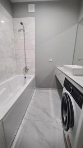 La salle de bains blanche est pourvue d'une baignoire et d'un lave-linge. dans l'établissement Irina apartament Stefan 64, à Chişinău
