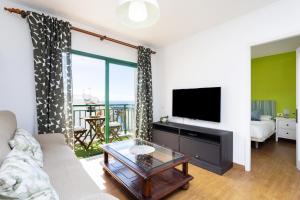 a living room with a couch and a tv at Nice 2 bd apartment by the sea in Playa San Juan in Playa de San Juan