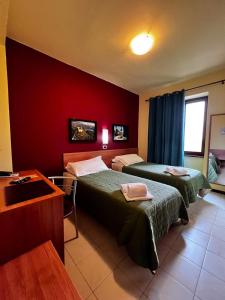 Habitación de hotel con 2 camas y pared roja en Hotel Erbaluce, en Caluso