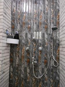 a shower in a bathroom with a stone wall at Kollolini Kolkata in Kolkata