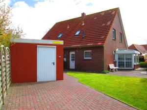una casa de ladrillo rojo con garaje blanco en Ostfrieslandtraum-mit-Kamin-und-Wintergarten en Dornumersiel