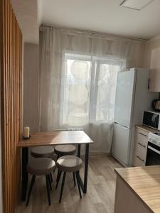 La cuisine est équipée d'une table, de tabourets et d'un réfrigérateur. dans l'établissement Apartment on Protozanova 21, à Öskemen