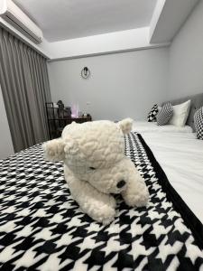un osito de peluche blanco grande sentado en una cama en 漫光時旅民宿-電子入住, en Taitung