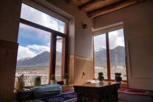 a room with a large window with a view of mountains at The Hermit Homestay in Leh