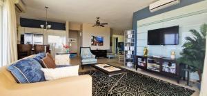 een woonkamer met een bank en een flatscreen-tv bij Apartment Royal Palm Resort in Willemstad