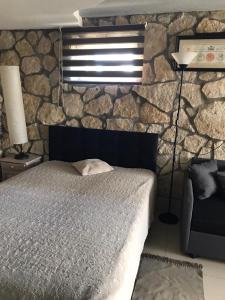 een slaapkamer met een bed en een stenen muur bij Studio Roxi in Bachowice