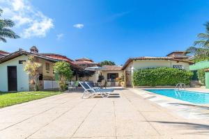a house with a swimming pool and a chair at Linda casa em Búzios a 50 m da Praia da Ferradura. in Búzios