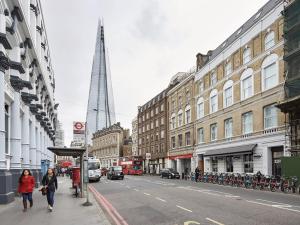 two people walking down a city street with a tall building at Luxury Collection - 2 Bedroom Apartment -Borough Market in London
