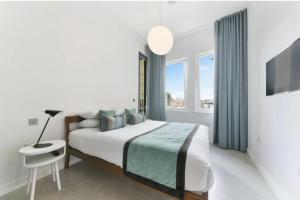 a white bedroom with a bed and a table and window at Luxury Collection - 2 Bedroom Apartment -Borough Market in London