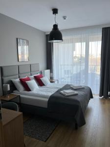 1 dormitorio con 1 cama grande con almohadas rojas en Apartament 215 - Modern Tower Gdynia, en Gdynia