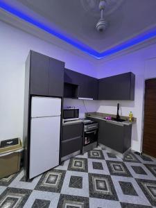 a kitchen with a white refrigerator and black cabinets at Lovely 5-Bed House Getaway Duplex in Accra in Accra
