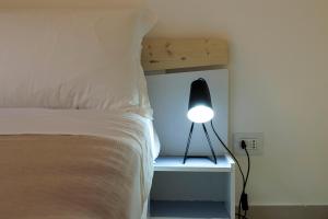 a bedroom with a bed with a lamp on a nightstand at Elsa d'Ortigia in Syracuse