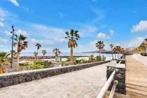 a boardwalk along a beach with palm trees and the ocean at Beautiful Apartment El Unicornio De Paula in Candelaria