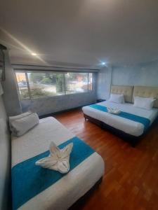 two beds in a room with a large window at Hotel Zafiro Boutique in Bogotá