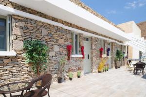 a stone house with a patio with chairs and plants at Sapphire Kythnos Suites in Mérikhas