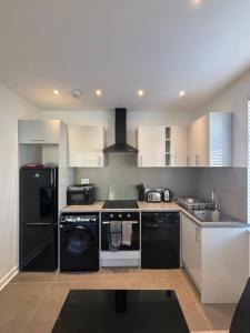 una cocina con armarios blancos y electrodomésticos negros en Access Euston, en Londres
