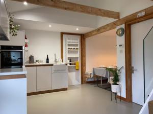 a kitchen with a table and a dining room at A Unique, Rural, Modern Annexe with Large Garden, Games, Tennis Court & EV Point in Chichester