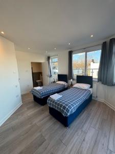 two beds in a room with wooden floors and windows at Access Euston in London