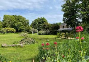 a garden with flowers and a house in the background at A Unique, Rural, Modern Annexe with Large Garden, Games, Tennis Court & EV Point in Chichester