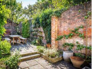 un giardino con tavolo e muro di mattoni di West Pallant Georgian Townhouse in City Centre with Courtyards, BBQ & Log Burners - Dogs Welcome! Chichester Holiday Properties a Chichester